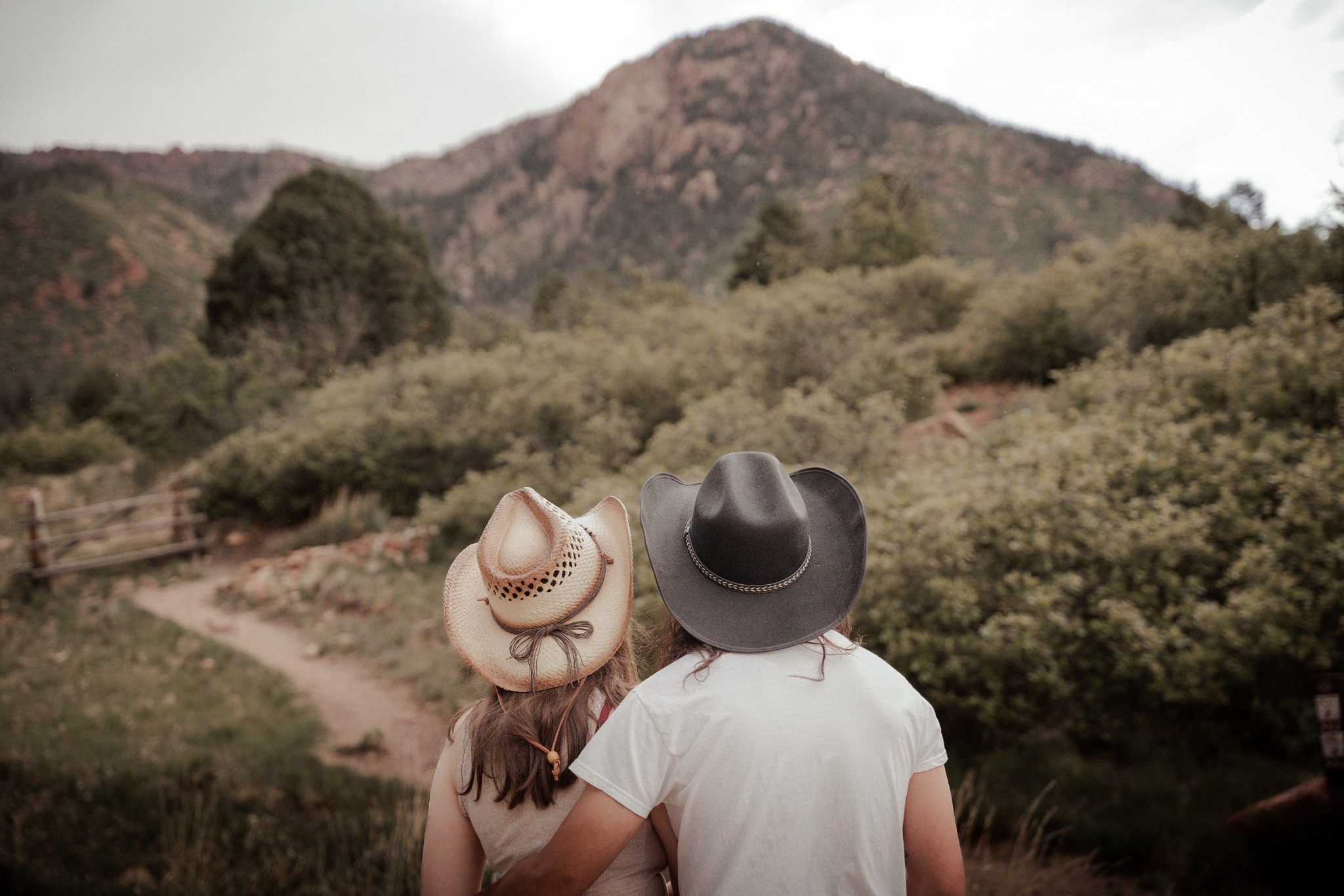Couple in cowboy hats looking toward a Colorado mountain