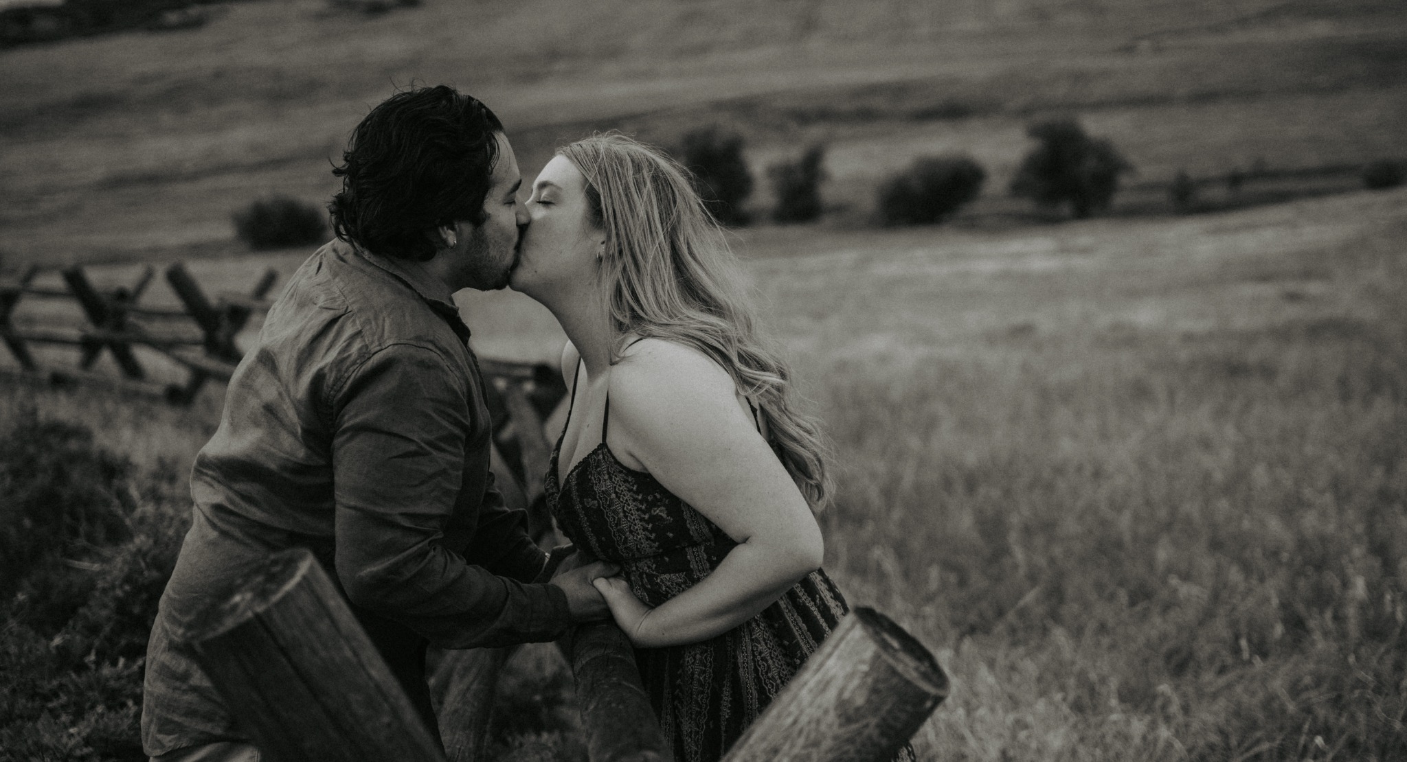 Black and white portrait of an engaged couple kissing