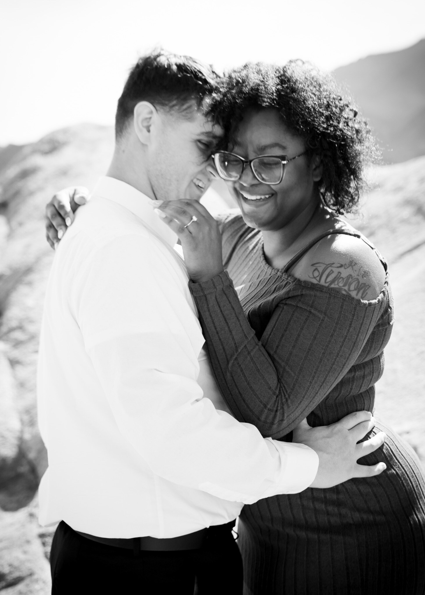 Black and white candid portrait of an engaged couple laughing together